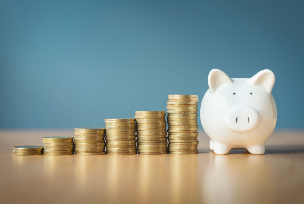 Stacked coins next to a white piggy bank