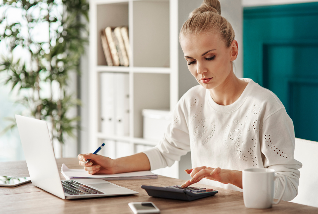 woman typing on calculator at desk